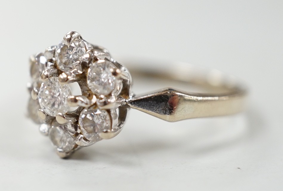 A modern 18ct white gold and seven stone diamond set hexagonal cluster ring, size O, gross weight 3.9 grams.